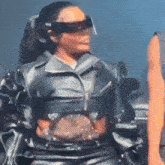 a woman wearing a leather jacket and sunglasses is walking on a stage .