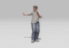 a man in a grey shirt and blue jeans is standing with his hands outstretched