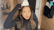 a woman in a black turtleneck is holding a piece of paper in her hand