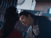 a man and a woman are looking at each other and the woman is wearing a red dress