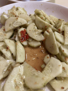 a white plate topped with sliced cucumbers and a red pepper