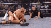 two wrestlers in a wrestling ring with a referee and a sign that says stan