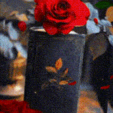 a red rose in a blue vase with a leaf on it