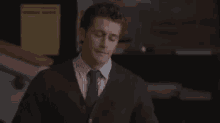 a man in a suit and tie is standing in a room and smiling .