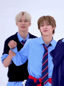 a boy in a blue shirt and tie is standing next to another boy