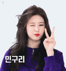 a woman in a purple sweater is making a peace sign with her fingers