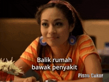 a woman is sitting at a table with the words balik rumah bawah penyakit written on the bottom