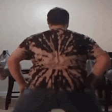 a man wearing a tie dye shirt is dancing in a living room .