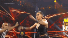 a woman is standing in a wrestling ring with a referee behind her .