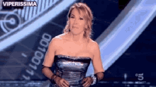 a woman in a strapless dress is standing on a stage with the words viperissima written on the bottom
