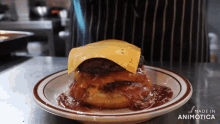 a hamburger with cheese on top of it is on a plate that says made in animatica