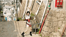 a girl is standing next to a bench with her arms in the air .