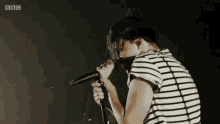 a woman singing into a microphone with bbc written on the bottom right