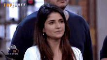 a woman stands in front of a sign that says " top chef "