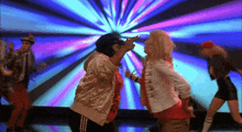 a group of people are dancing in front of a colorful light show