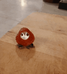 a strawberry with a face on it sits on a wooden cutting board