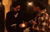 two men are standing next to each other and one has a glowing object in his hand