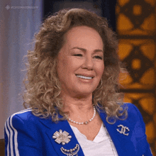 a woman wearing a blue jacket with chanel brooches on her jacket