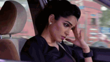 a woman sitting in the back seat of a car with her hand on her head