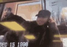 a man in a hat is standing in front of a window in a blurry photo .