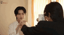 two men are holding hands and one is taking a picture of the other with a camera .