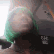 a woman with green hair is sitting on a plane with her head down .