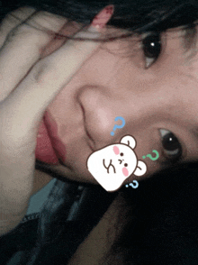 a close up of a woman 's face with a sticker of a bear with a question mark above it