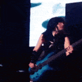a woman is playing a blue bass guitar in a dark room .