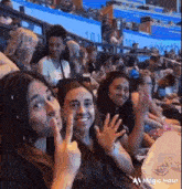 a group of people are sitting in a stadium making funny faces and waving .