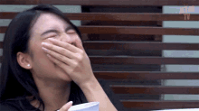 a woman is laughing with her hand over her mouth