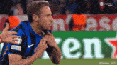 a soccer player is being held by another player in front of a green heineken sign
