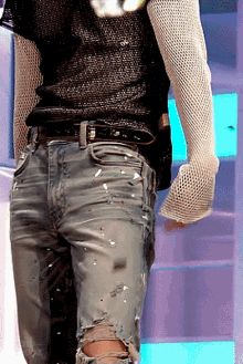 a person wearing ripped jeans and a fishnet top