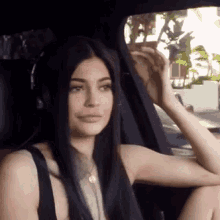 a woman is sitting in the back seat of a car wearing headphones and a necklace .