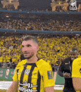 a man wearing a yellow and black jersey that says roshn