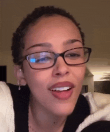 a woman wearing glasses and earrings is smiling .