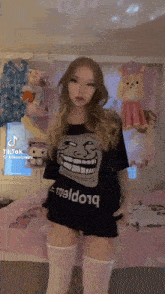 a woman wearing a troll face t-shirt and knee high socks is standing in a room .