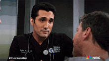 a man with a stethoscope around his neck is talking to another man in a chicago medical center uniform