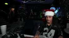 a man wearing a santa hat is sitting in front of a christmas tree