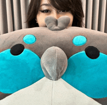 a woman covering her face with a stuffed animal that looks like a dolphin
