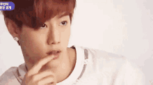 a young man with red hair is looking at the camera while holding his finger to his lips .