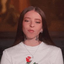 a woman is wearing a white shirt with a rose on it