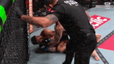 a man in a black shirt that says ufc on it is wrestling another man