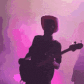 a man in a cowboy hat is playing a guitar in front of a purple background .