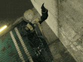 a man in a black jacket and yellow gloves stands in front of a wall