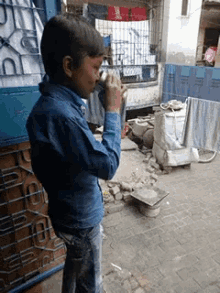 a young boy in a blue shirt drinks from a small cup