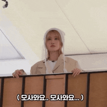 a woman wearing a white hat is looking over a railing with a caption in korean