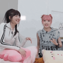 two girls with pink hair are sitting next to each other on a couch .