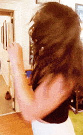 a woman with long brown hair is dancing in a room