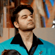 a man in a blue suit and black shirt looks to his left