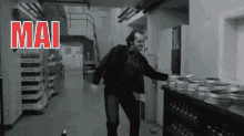 a man is standing in a hallway in front of a shelf of film rolls .